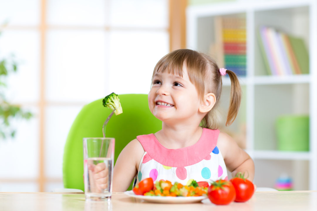 Kid eats healthy vegetables meal in home or nursery
