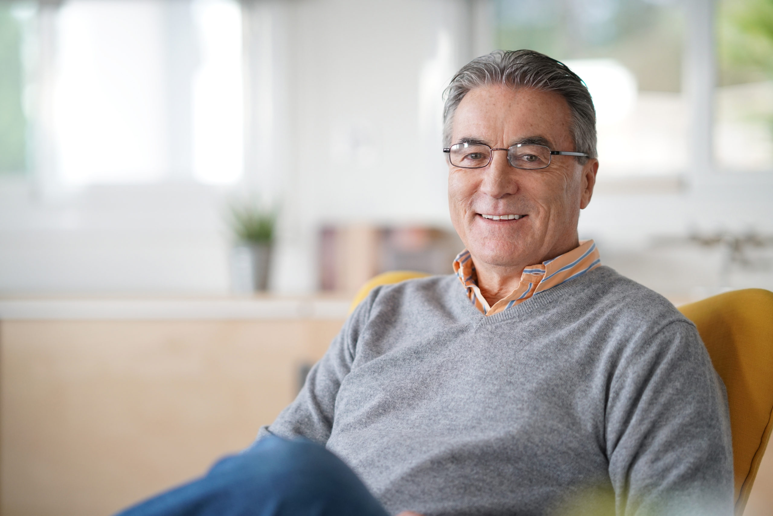 Smiling senior man with eyeglasses relaxing in armchair