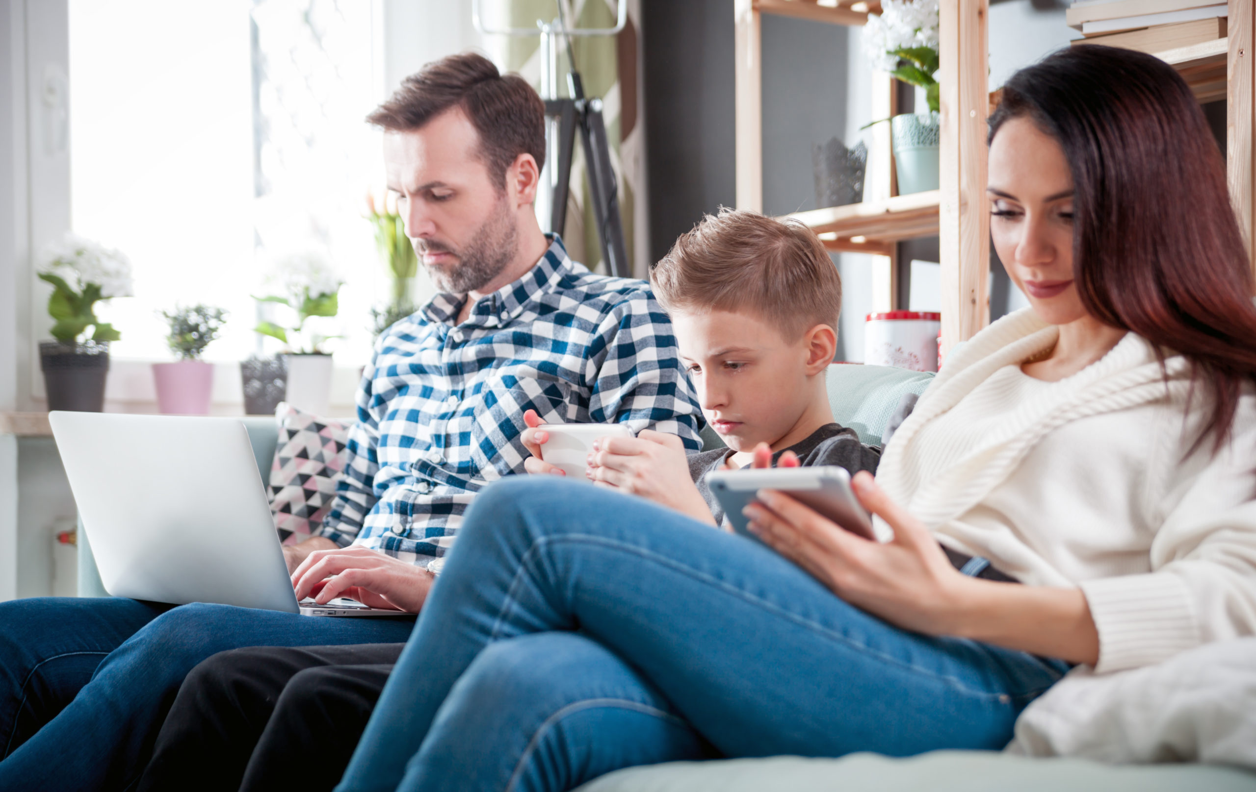 Family with laptop, tablet and smartphone at home, everyone using digital devices