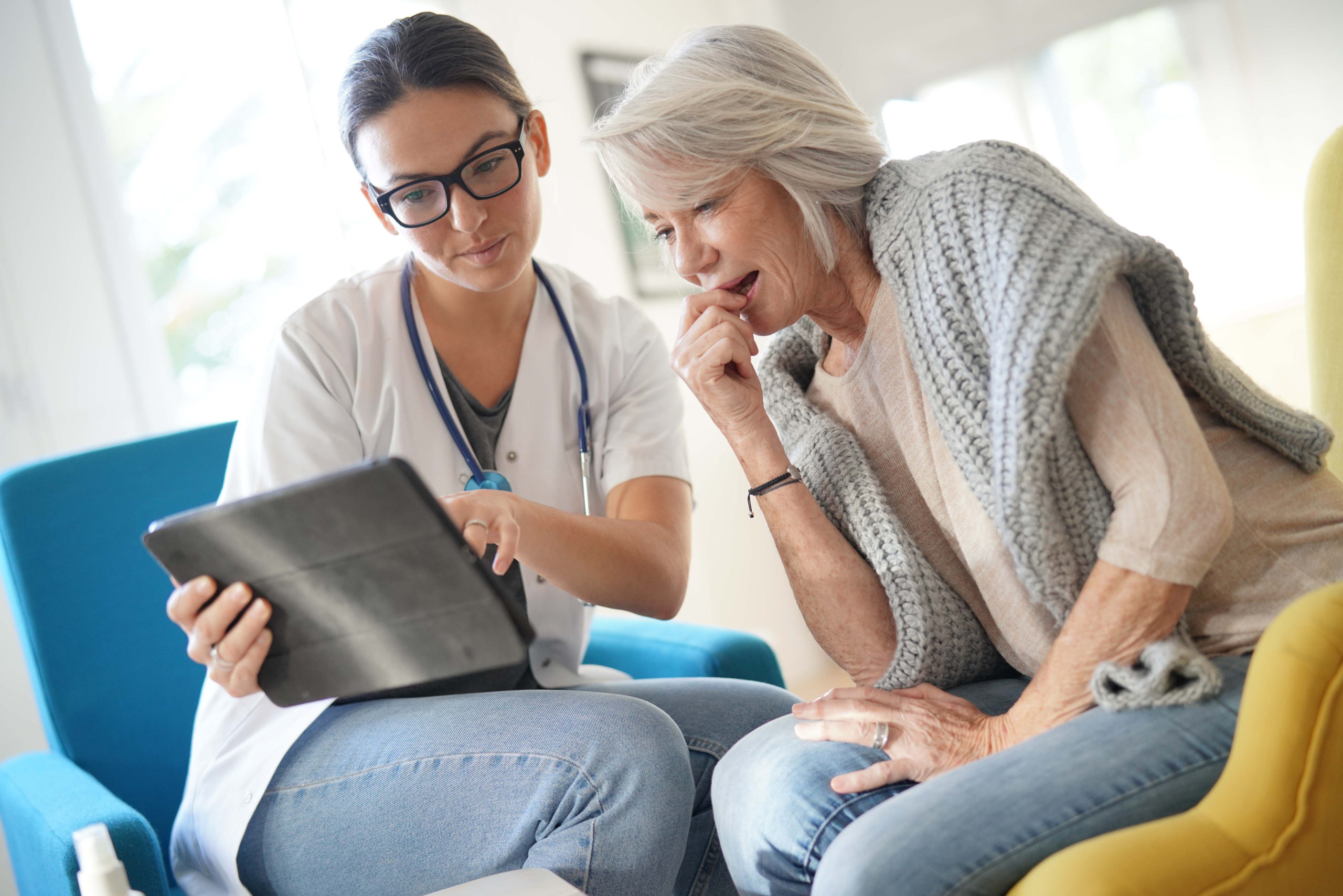 Doctor going through results and medication on tablet with senior patient