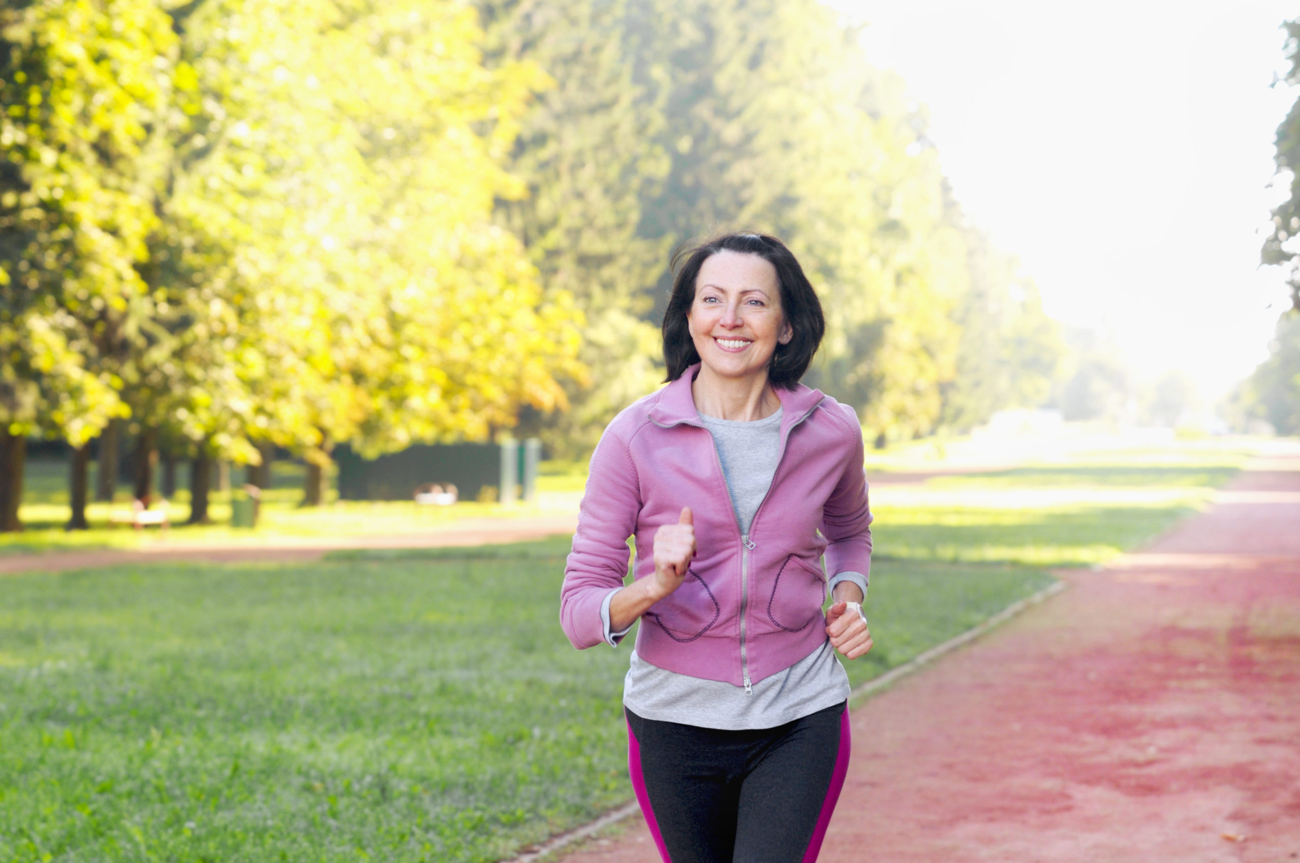 Portrait of elderly woman running in the park in early morning. Attractive looking mature woman keeping fit and healthy.
