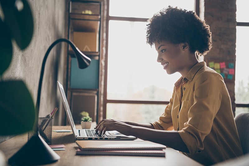 Profile side photo of smart cool afro american girl entrepreneur sit table use laptop, work presentation in office loft workplace