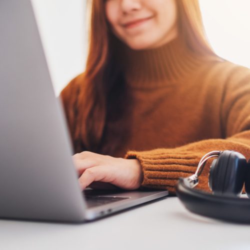 Closeup image of a beautiful woman working and typing on laptop computer in office